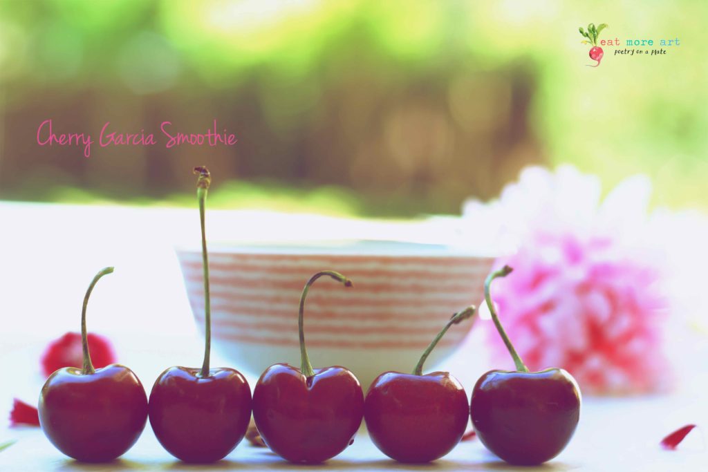 A close up shot of 5 cherries in a line, with smoothie bowl in the background