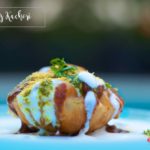 Raj Kachori drizzled with yogurt, chutneys, and garnished with sev and coriander