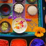 An overhead shot of a colorful tray of thandai, it's ingredients, and holi colors