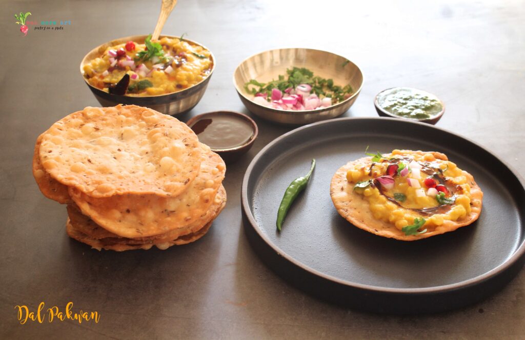 A side shot of Dal Pakwan served on a platter with Pakwans, Daal and condiments on the side