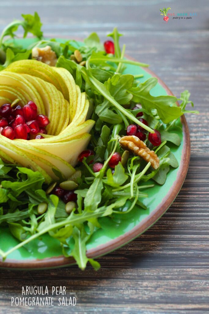 A close up side shot of arugula pear pomegranate salad 